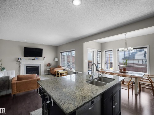 Kitchen island featuring a double basin sink, chrome faucet, and granite countertop - 3247 15 Avenue Nw, Edmonton, AB 
