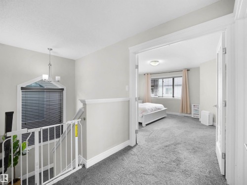Upper-level landing with plush gray carpeting and a distinctive arched window - 3247 15 Avenue Nw, Edmonton, AB 