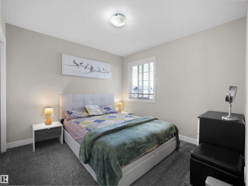Carpeted bedroom with neutral wall tones and a window featuring white blinds - 3247 15 Avenue Nw, Edmonton, AB 