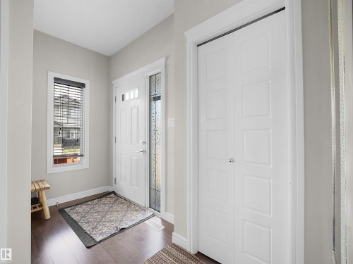 Entryway featuring dark wood-finish flooring, light grey walls, white trim, and a white paneled entry door with decorative glass sidelight - 3247 15 Avenue Nw, Edmonton, AB 