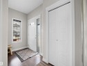 Entryway featuring dark wood-finish flooring, light grey walls, white trim, and a white paneled entry door with decorative glass sidelight - 3247 15 Avenue Nw, Edmonton, AB 