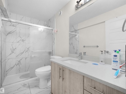 Bathroom featuring a single vanity with wood-finish cabinetry and a light-toned countertop - 3247 15 Avenue Nw, Edmonton, AB 
