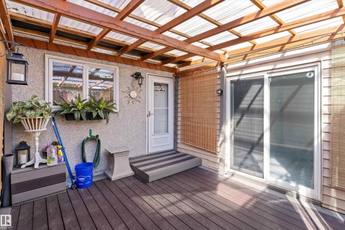 Covered patio featuring a translucent roof, wood-finish decking, and a sliding glass door - 6734 36A Avenue, Edmonton, AB 