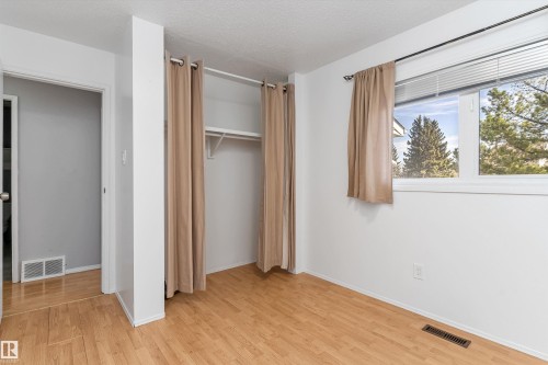 Interior room featuring wood-finish flooring, white painted walls, and a window with blinds - 6734 36A Avenue, Edmonton, AB 