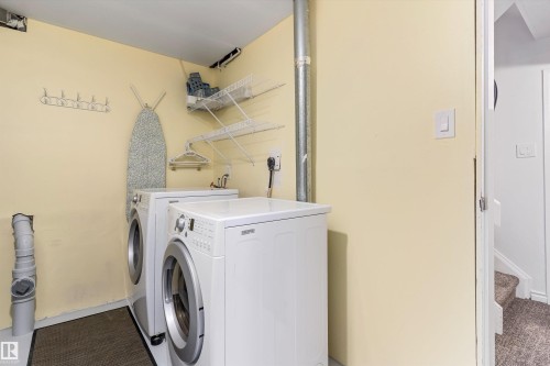 Dedicated laundry area featuring a front-loading washing machine, a front-loading dryer, built-in wire shelving, and a wall-mounted hook rack - 6734 36A Avenue, Edmonton, AB 