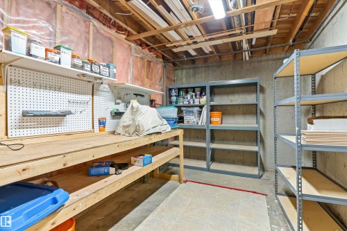 Unfinished basement space featuring a wooden workbench, wall-mounted pegboard, and multiple metal shelving units for organized storage - 6734 36A Avenue, Edmonton, AB 