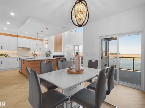Open concept dining area with wood-finish herringbone flooring and a modern chandelier - 209 Crystal Creek Dr Nw, Leduc, AB - Indoor Photo Showing Dining Room