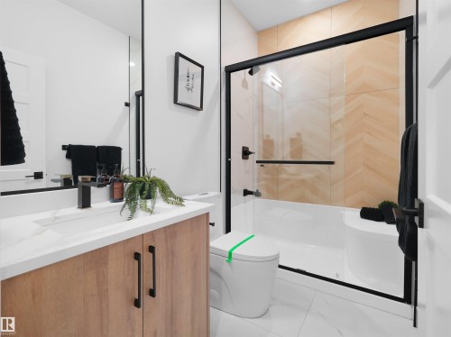 Modern bathroom featuring a wood-finish vanity with a white countertop and integrated sink - 209 Crystal Creek Dr Nw, Leduc, AB - Indoor Photo Showing Bathroom