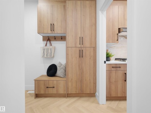 Herringbone wood-finish flooring extending into a built-in storage bench with an integrated drawer and wall-mounted coat hooks - 209 Crystal Creek Dr Nw, Leduc, AB - Indoor Photo Showing Other Room