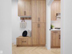 Herringbone wood-finish flooring extending into a built-in storage bench with an integrated drawer and wall-mounted coat hooks - 