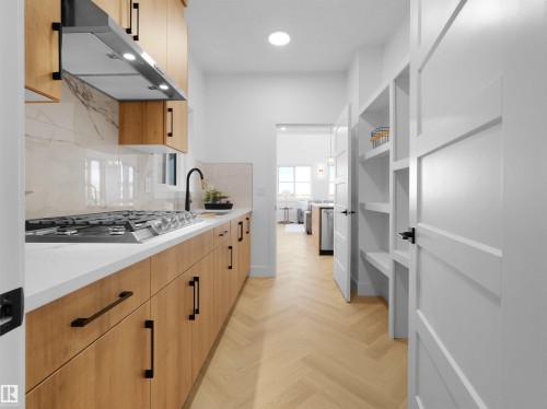 Modern kitchen featuring natural wood cabinetry, white countertops, a gas range with a stainless steel hood, a large format tile backsplash, and herringbone wood-finish flooring - 209 Crystal Creek Dr Nw, Leduc, AB - Indoor Photo Showing Kitchen