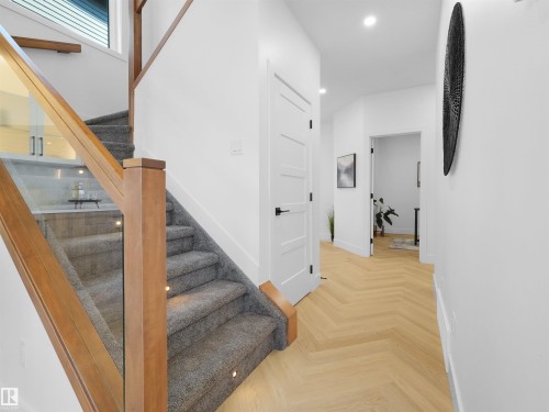 Contemporary staircase with wood-finish handrails and glass balusters - 209 Crystal Creek Dr Nw, Leduc, AB - Indoor Photo Showing Other Room