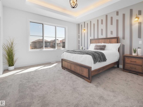 Room featuring a tray ceiling with recessed lighting, a decorative accent wall, and light gray carpeting - 209 Crystal Creek Dr Nw, Leduc, AB - Indoor Photo Showing Bedroom