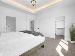 Carpeted bedroom featuring a tray ceiling with cove lighting and a decorative chandelier - 