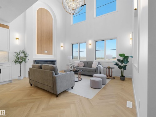 Vaulted ceilings with an elegant chandelier, a prominent fireplace with an arched wood-finish accent, herringbone wood-finish flooring, and multiple windows providing ambient light - 209 Crystal Creek Dr Nw, Leduc, AB - Indoor