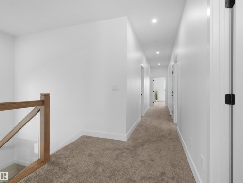 Carpeted hallway featuring recessed lighting, white walls, and a wood and glass railing - 209 Crystal Creek Dr Nw, Leduc, AB - Indoor Photo Showing Other Room