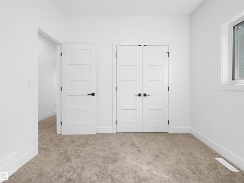 Soft carpeted flooring throughout, featuring a double-door closet with matte black hardware - 209 Crystal Creek Dr Nw, Leduc, AB - Indoor Photo Showing Other Room