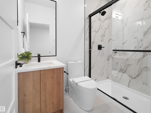 Modern bathroom featuring a wood-finish vanity with a white countertop and matte black fixtures - 209 Crystal Creek Dr Nw, Leduc, AB - Indoor Photo Showing Bathroom