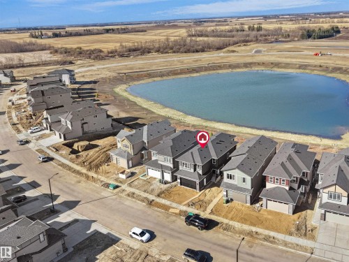 Modern residential development featuring a community pond and surrounding open fields - 209 Crystal Creek Dr Nw, Leduc, AB - Outdoor With View