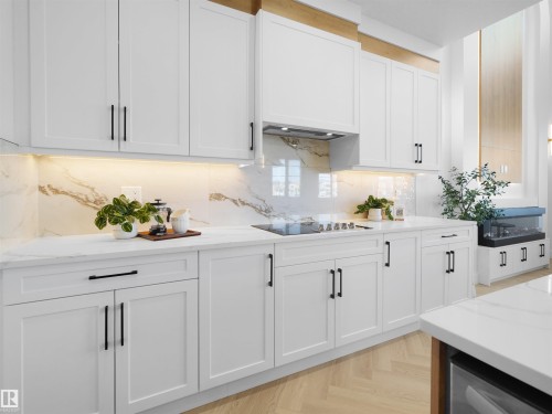 Modern kitchen featuring white shaker cabinetry with matte black hardware, white countertops, and a white marble-look backsplash - 209 Crystal Creek Dr Nw, Leduc, AB - Indoor Photo Showing Kitchen With Upgraded Kitchen