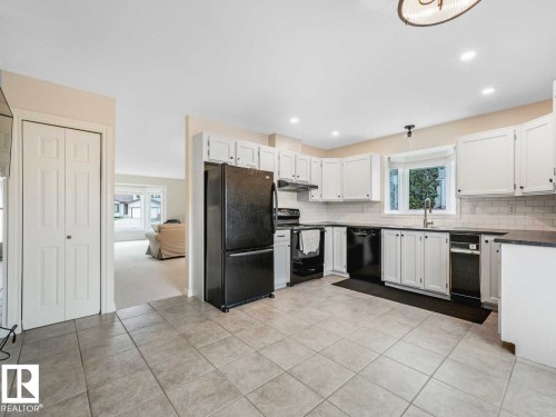Kitchen featuring tile flooring, white cabinetry, dark countertops, a subway tile backsplash, and a bay window - 4011 104 Street, Edmonton, AB - Indoor Photo Showing Kitchen