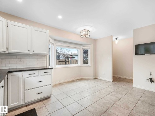 Kitchen and dining area featuring a bay window, recessed lighting, white cabinetry with dark hardware, and a subway tile backsplash - 4011 104 Street, Edmonton, AB - Indoor Photo Showing Kitchen