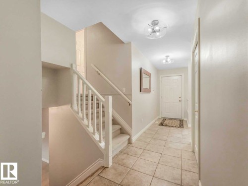 Foyer featuring a light neutral color palette, ceramic tile flooring, and a white paneled entry door - 4011 104 Street, Edmonton, AB - Indoor Photo Showing Other Room