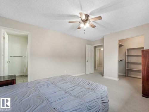Carpeted bedroom with a ceiling fan, featuring a walk-in closet with built-in shelving, and doorways to additional spaces - 4011 104 Street, Edmonton, AB - Indoor Photo Showing Bedroom