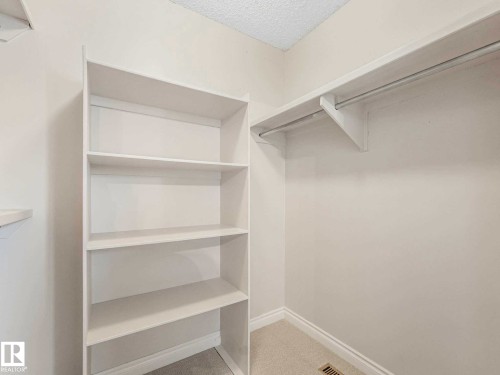 Walk-in closet featuring white built-in shelving, a hanging rod, and light-colored carpeting - 4011 104 Street, Edmonton, AB - Indoor With Storage