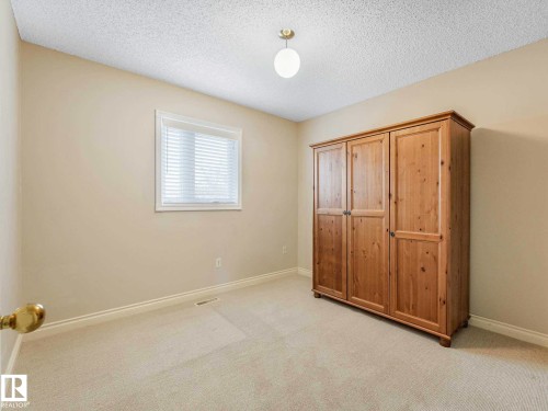 Carpeted room featuring a single window with blinds, a ceiling-mounted light fixture, and neutral-toned walls - 4011 104 Street, Edmonton, AB - Indoor
