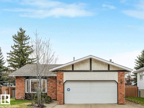 Brick and stucco front exterior featuring a double garage door, an asphalt shingle roof, and mature perimeter trees - 4011 104 Street, Edmonton, AB - Outdoor