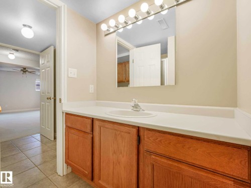 Bathroom vanity featuring a single basin, light-toned countertop, and wood-finish cabinetry - 4011 104 Street, Edmonton, AB - Indoor Photo Showing Bathroom