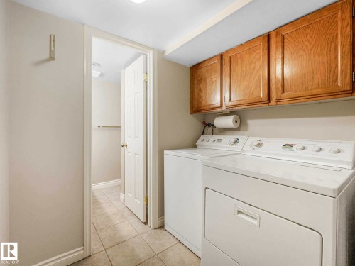 Utility area featuring overhead wood cabinetry and tile flooring - 4011 104 Street, Edmonton, AB - Indoor Photo Showing Laundry Room