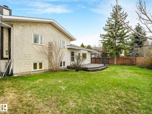 Rear exterior featuring stucco siding, multiple windows, and a multi-level deck with dark composite decking - 4011 104 Street, Edmonton, AB - Outdoor