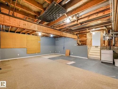 Expansive basement area featuring exposed ceiling joists, grey painted walls, and a combination of carpeted and concrete flooring - 4011 104 Street, Edmonton, AB - Indoor Photo Showing Basement