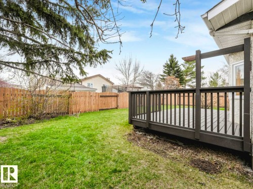 Private backyard featuring a wooden privacy fence, a spacious deck with dark grey railings, and an expansive lawn area - 4011 104 Street, Edmonton, AB - Outdoor