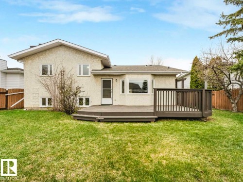 Spacious backyard featuring a large composite deck with railing, a grass lawn, and a light-colored stucco exterior - 4011 104 Street, Edmonton, AB - Outdoor With Deck Patio Veranda