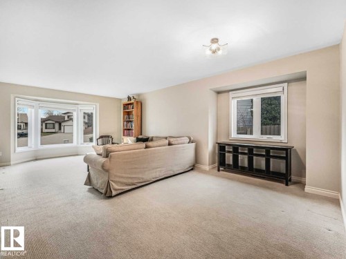 Bright living area featuring a large bay window, neutral carpet, and recessed wall niche with window - 4011 104 Street, Edmonton, AB - Indoor