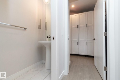 Pedestal sink with a circular wall-mounted light fixture, rectangular mirror, and light-toned wall paint - 1448 Darby Green Green, Edmonton, AB - Indoor