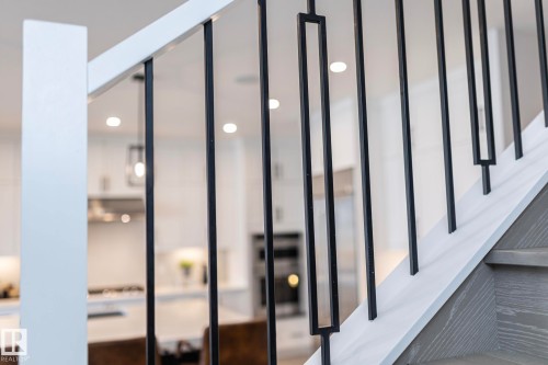 Staircase with contemporary black metal balusters, white newel post, and wood-finish treads - 1448 Darby Green Green, Edmonton, AB - Indoor Photo Showing Other Room