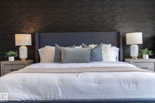 Textured accent wall, winged fabric headboard, and matching wood-finish nightstands with drawer storage - 1448 Darby Green Green, Edmonton, AB - Indoor Photo Showing Bedroom