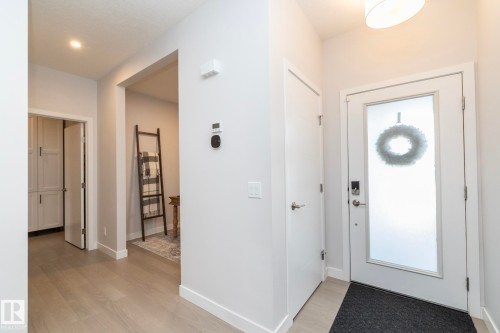 Entryway featuring a white door with frosted glass panel, light-toned wood-finish flooring, white baseboards, and neutral wall tones - 1448 Darby Green Green, Edmonton, AB - Indoor Photo Showing Other Room