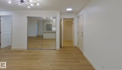 Spacious room featuring wood-finish flooring and a contemporary chandelier - 