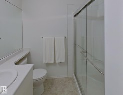 Bathroom featuring a glass-enclosed shower, white tile surround, vanity with an integrated sink, and a large wall mirror - 