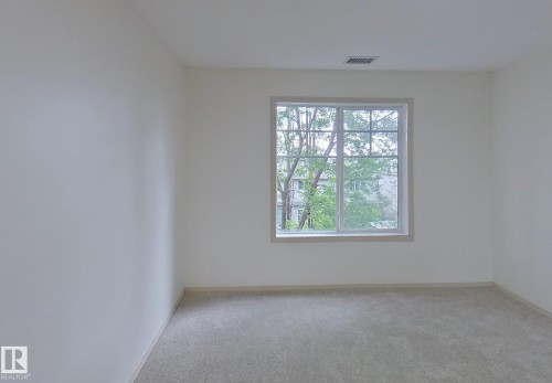Bright room with a large grid-pattern window, light-colored carpeting, white walls, and a circular overhead light fixture - 353 2096 Blackmud Creek Drive, Edmonton, AB - Indoor Photo Showing Other Room