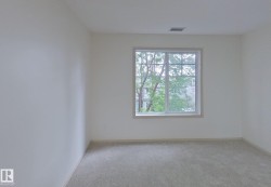 Bright room with a large grid-pattern window, light-colored carpeting, white walls, and a circular overhead light fixture - 