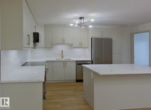 Contemporary kitchen featuring light-toned cabinetry, white countertops, a subway tile backsplash, stainless steel appliances, and wood-finish flooring - 353 2096 Blackmud Creek Drive, Edmonton, AB - Indoor Photo Showing Kitchen With Upgraded Kitchen