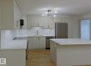 Contemporary kitchen featuring light-toned cabinetry, white countertops, a subway tile backsplash, stainless steel appliances, and wood-finish flooring - 353 2096 Blackmud Creek Drive, Edmonton, AB  - Indoor Photo Showing Kitchen With Upgraded Kitchen 
