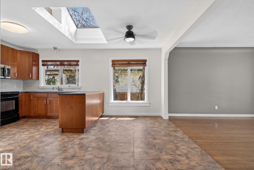 Kitchen with skylight, wood cabinetry, dark countertops, and tile flooring - 10409 83 Street, Edmonton, AB - Indoor Photo Showing Kitchen With Double Sink