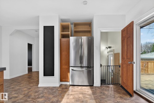 Kitchen area featuring a stainless steel French door refrigerator, wood-finish cabinetry, and a full-height chalkboard panel - 10409 83 Street, Edmonton, AB - Indoor